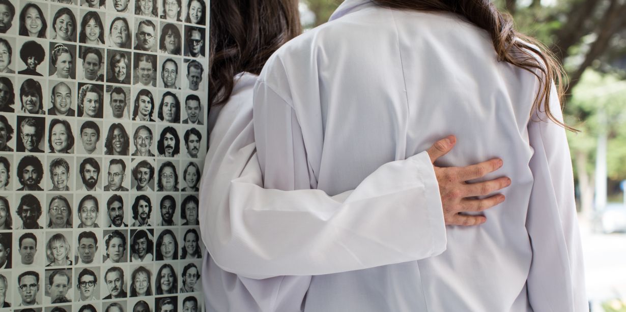 two students embrace in white coats