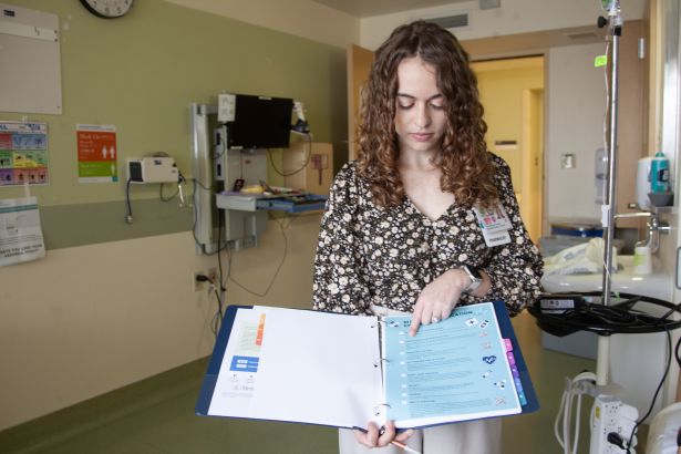 Gordon points to a list of medications in a binder.