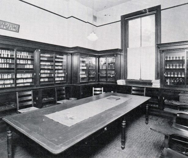 room with a large window holding glass cases filled with artifacts and a large table in the center.