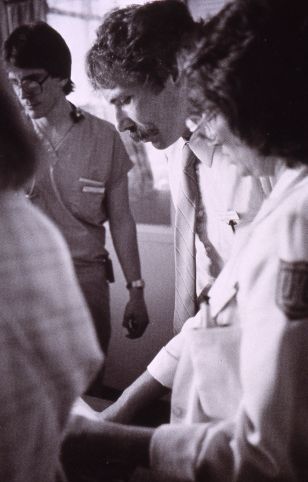 Guglielmo standing among clinicians in a hospital ward