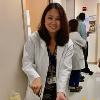 Reyles-Derry in white coat cutting a cake