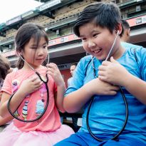 children wearing stethoscopes listen to their own heartbeats.