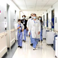 Several masked health care providers walk through a hospital hallways