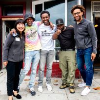 Zhou smiles with 4 people in front of barbershop