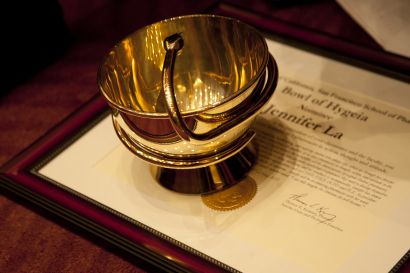 Golden bowl with a snake figurine, on top of a certificate reading Jennifer La