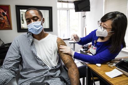 Zhou gives a masked man a vaccination