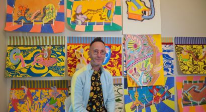 Walter in front of his artwork depicting colorful science characters
