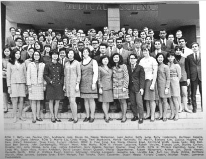 A group of men and women pose on the steps of a medical building