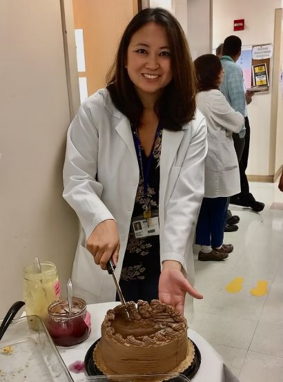 Reyles-Derry in white coat cutting a cake