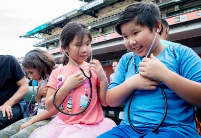 children wearing stethoscopes listen to their own heartbeats.