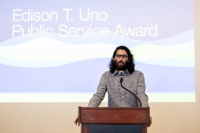 Diaz speaking at a podium in front of a graphic that reads Edison T. Uno Public Service Award