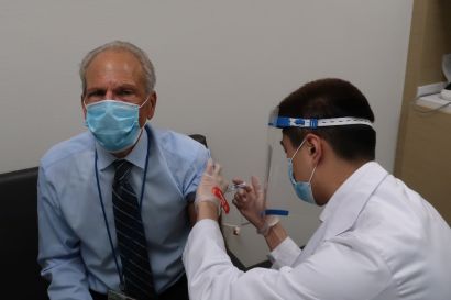 Li injects Guglielmo with the flu vaccine.