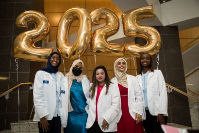 Five pharmacy students standing in front of gold balloons that read 2025