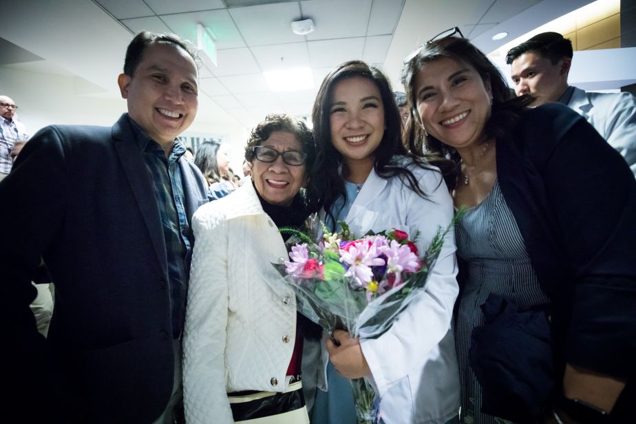 student holding bouquet surrounded by family members, all smiling.