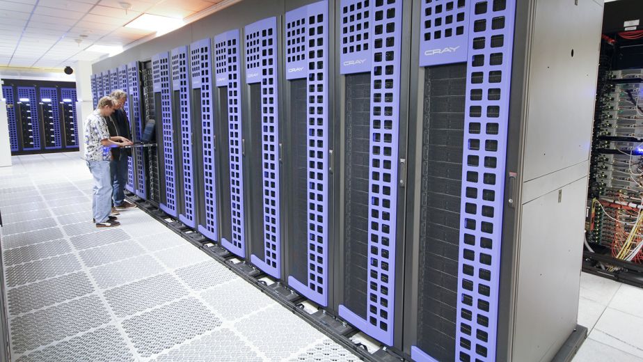 two people stand next to a Cray supercomputer