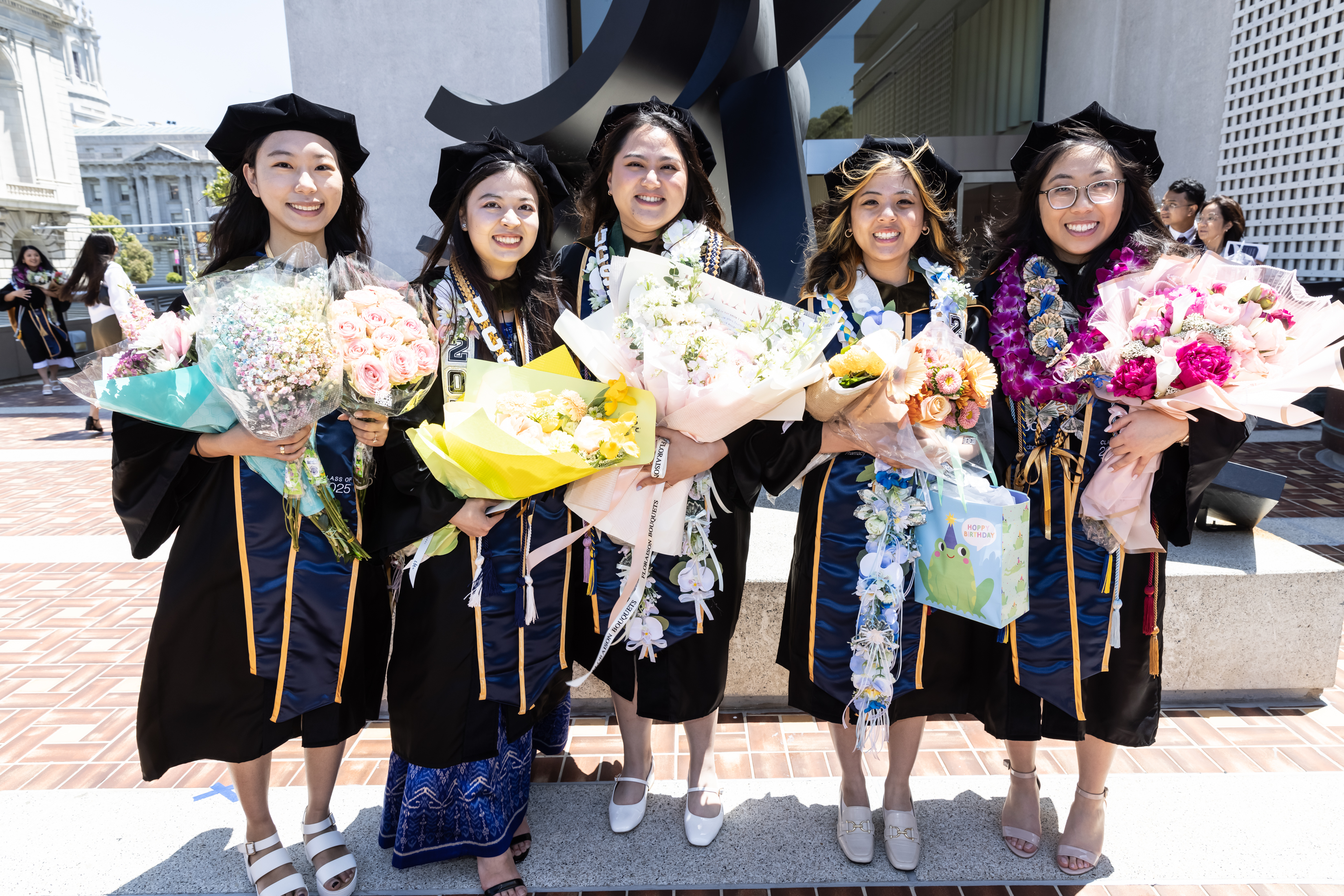 PharmD graduates pose after Commencement ceremony with flowers