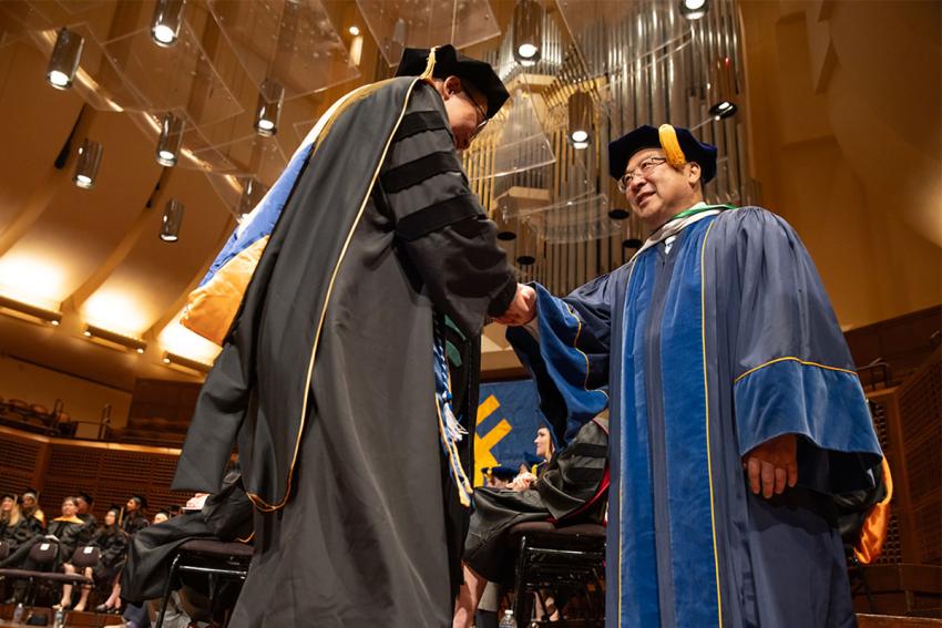 Brian Komoto shakes the hand of a graduate at commencement