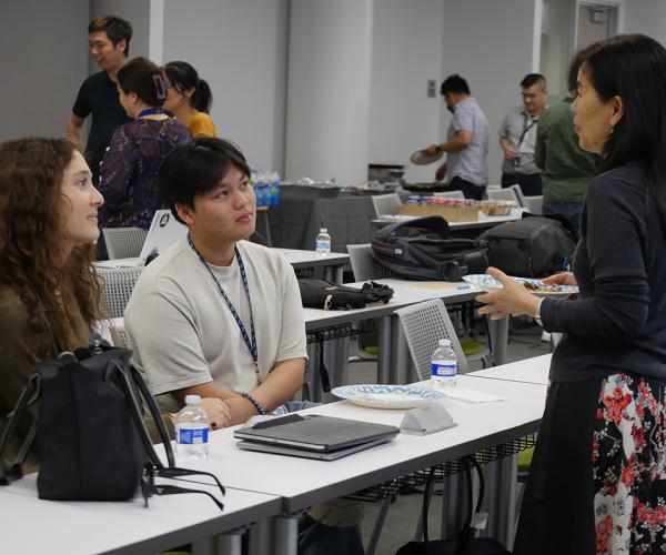 Two students in AICD3 class with professor Chun standing