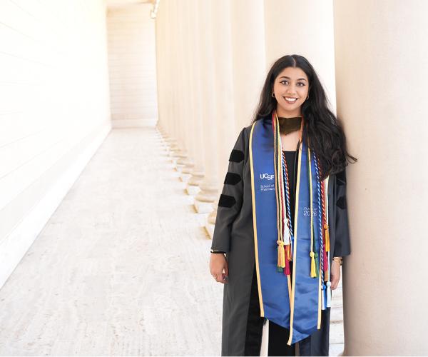 Rhea Misra in commencement attire with white columns in background