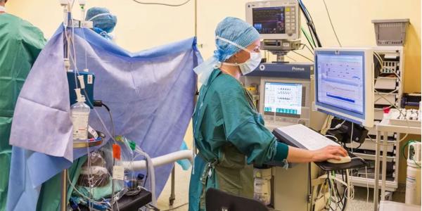 masked health care professional looks at computer screen in an operating room 