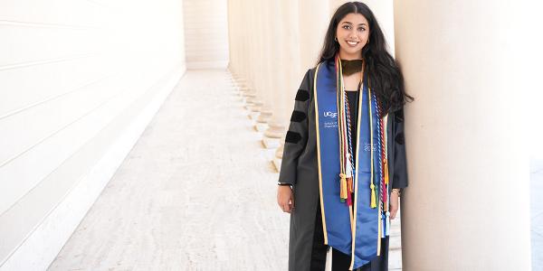 Rhea Misra in commencement attire with white columns in background
