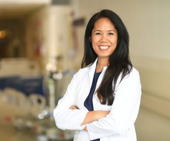 Jennifer Cocohoba in a white coat standing in a hospital hallway