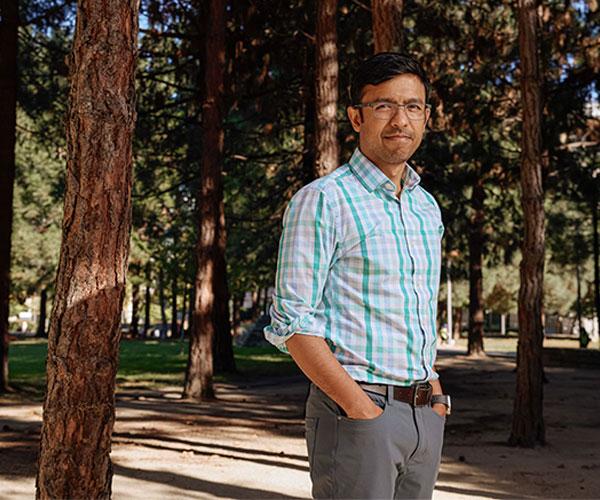 Aashish Manglik standing in a wooded area on the UCSF campus 